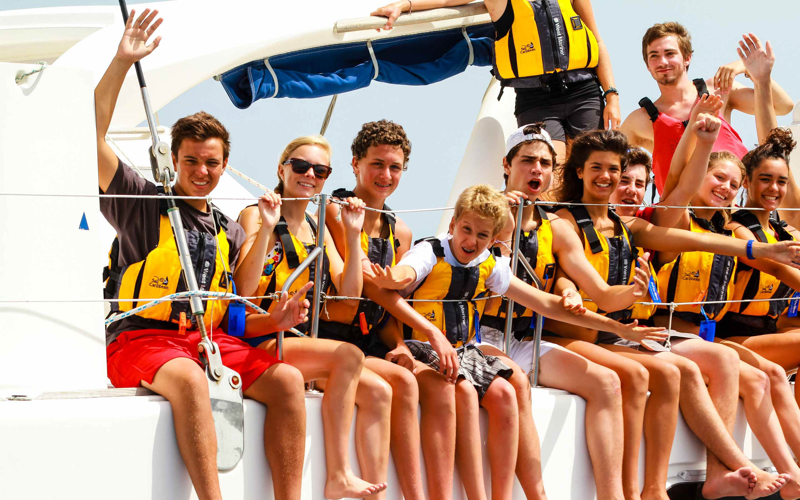 A group of people on a boat waving their life jackets.