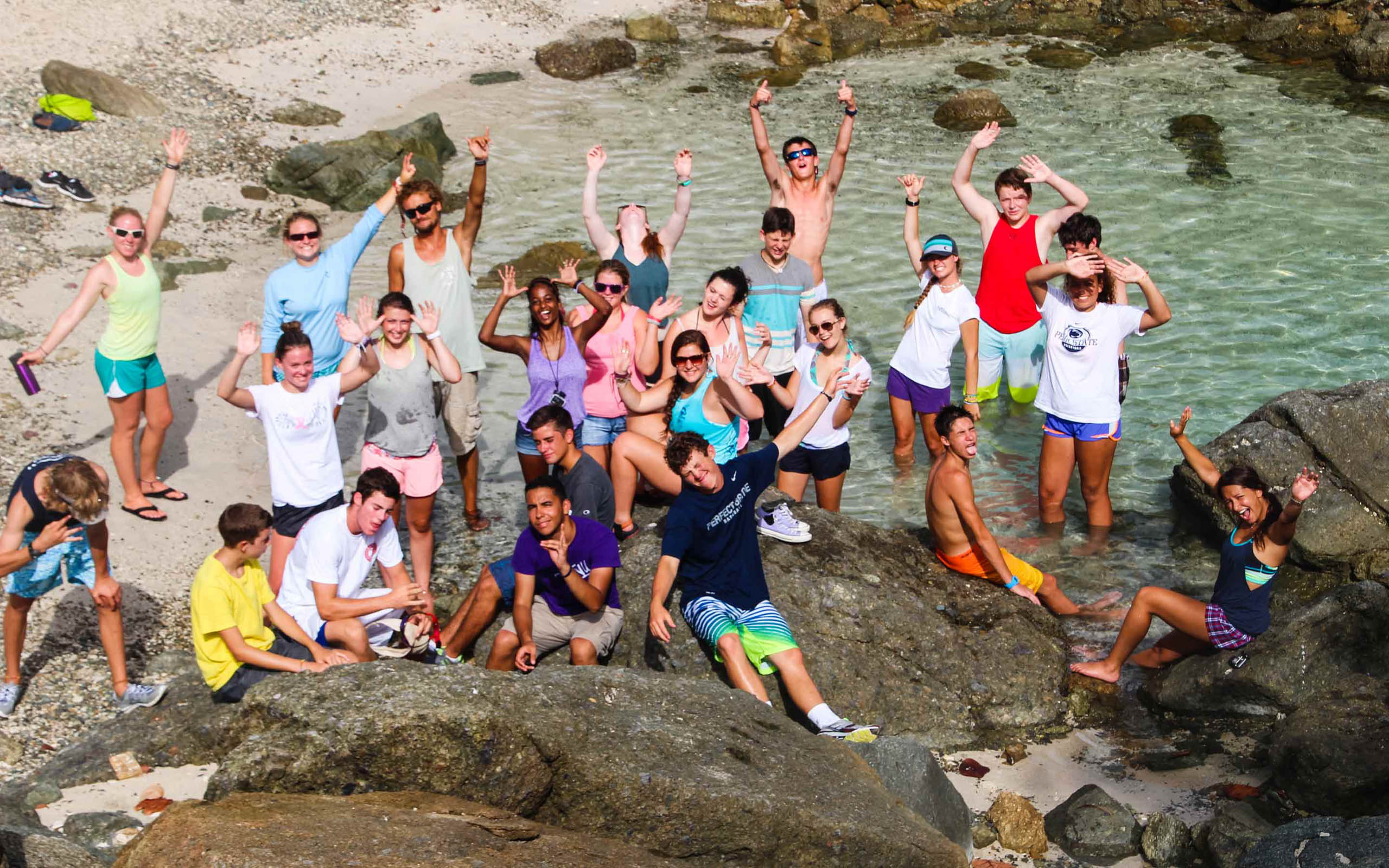 A group of people posing on rocks in the water.