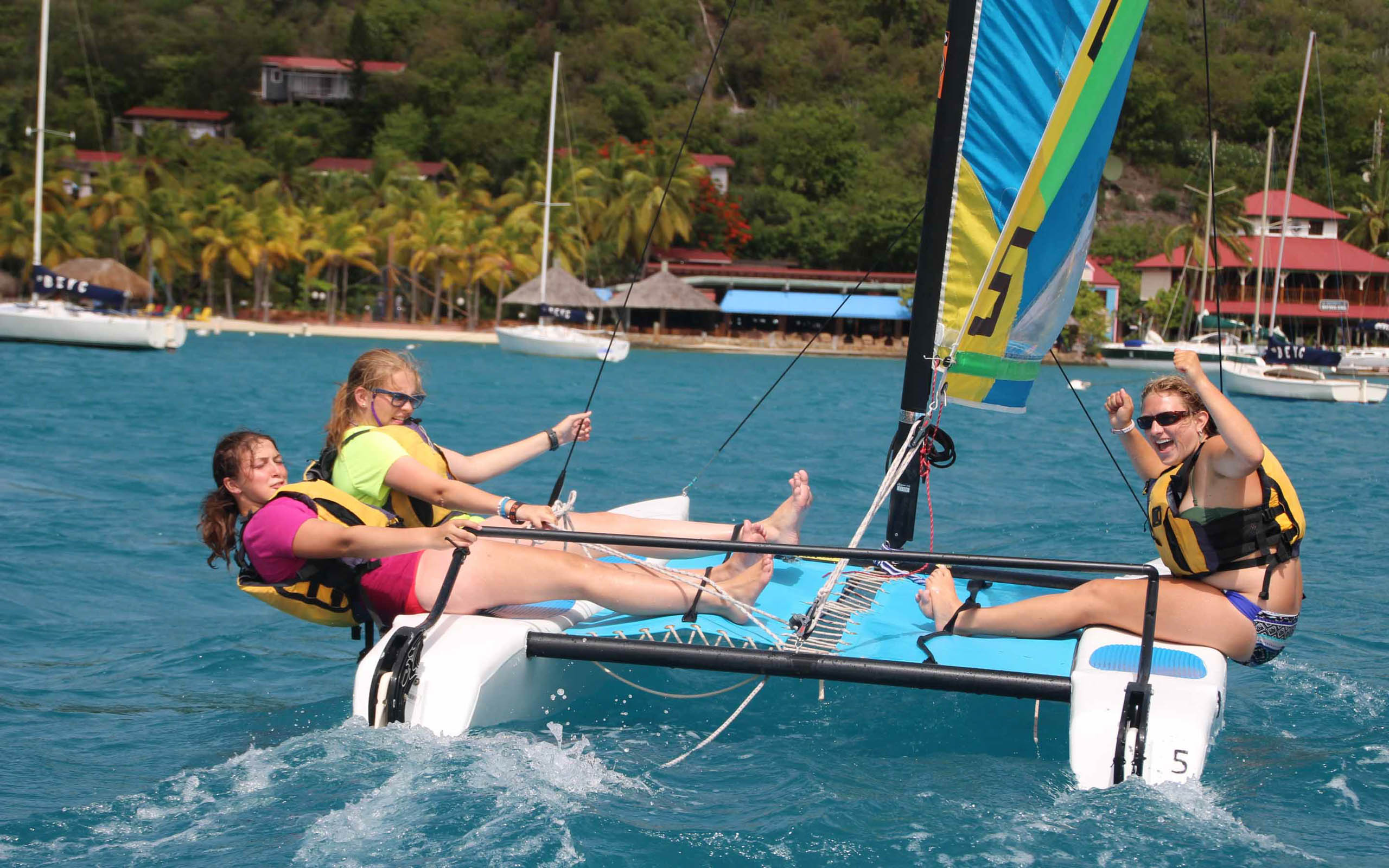 A group of girls on a sailboat in the ocean.