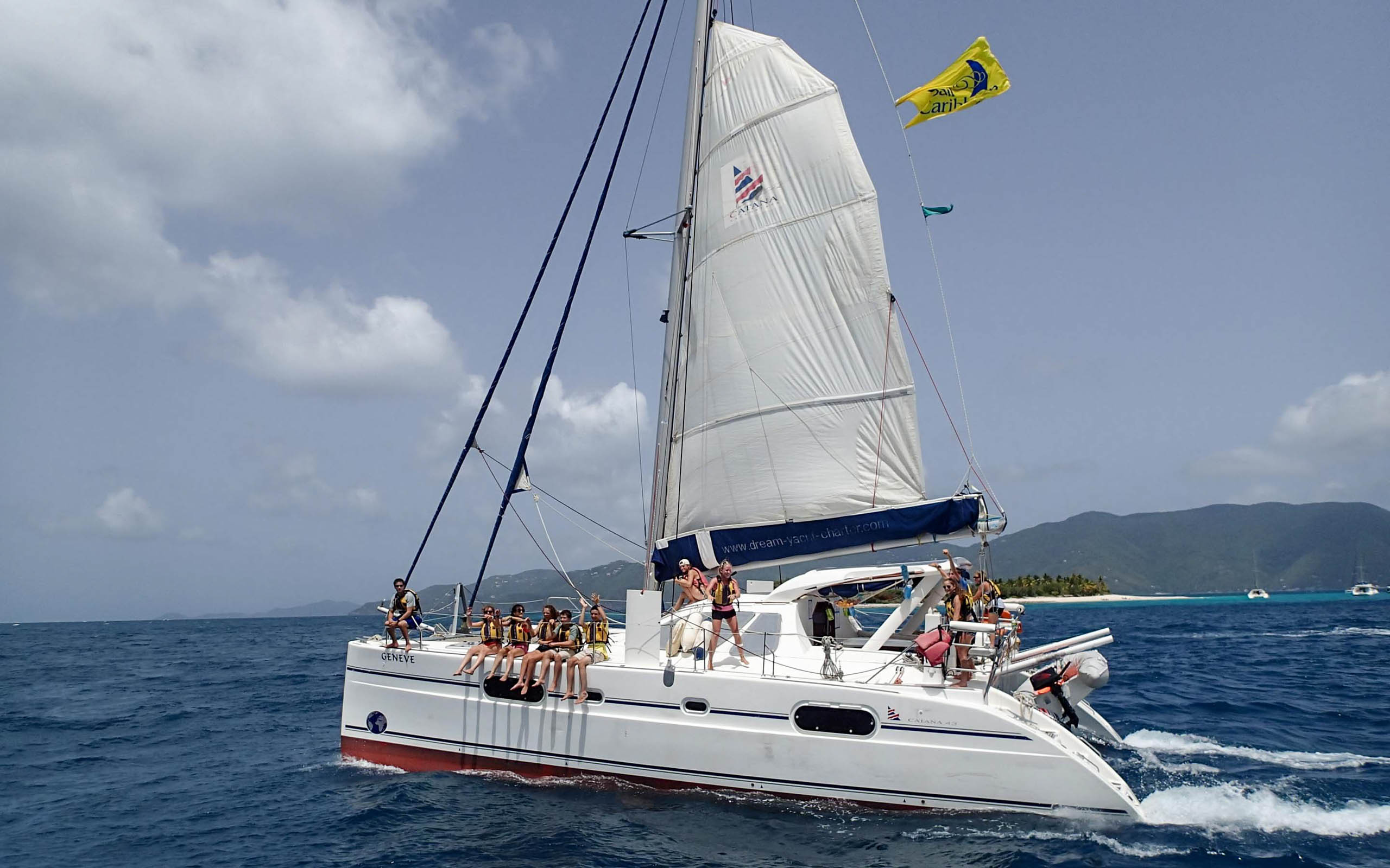 A group of people on a white catamaran in the ocean.