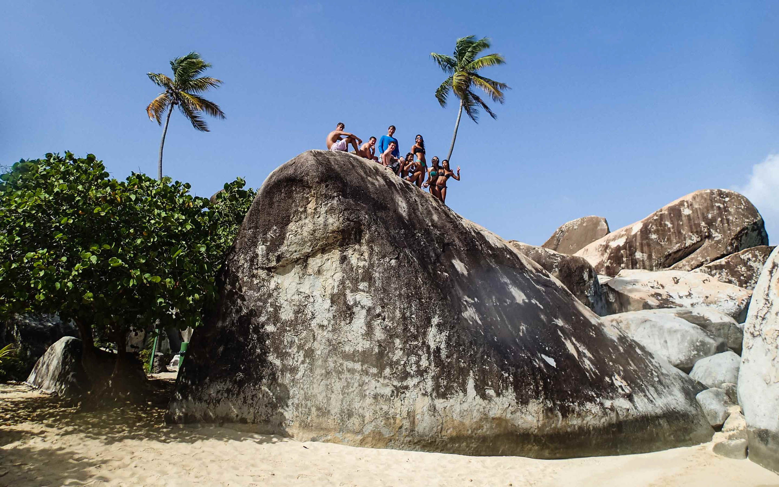 A group of people standing on top of a large rock.