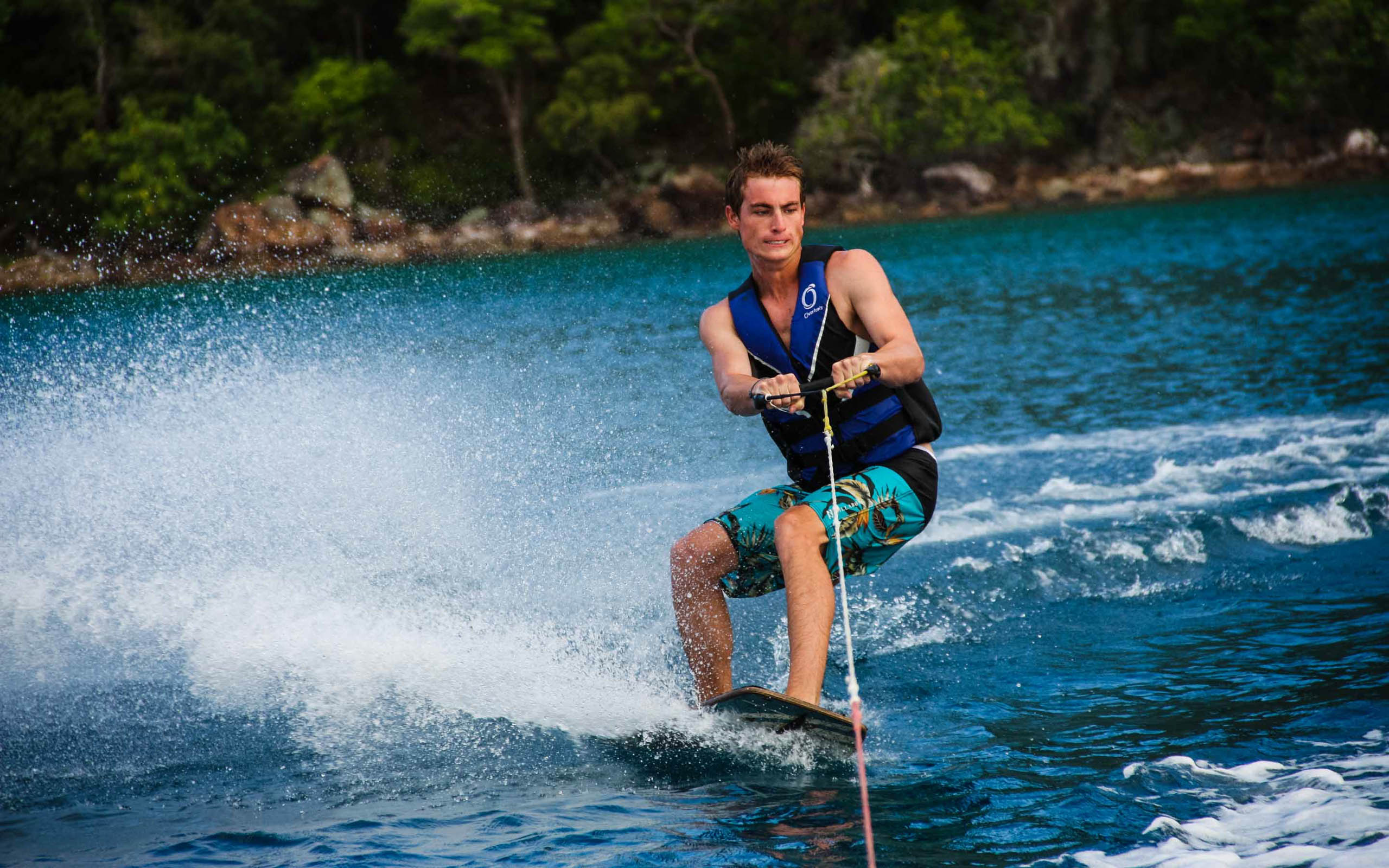 A man is water skiing in the blue water.