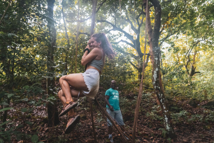 A woman is swinging on a tree in the forest.