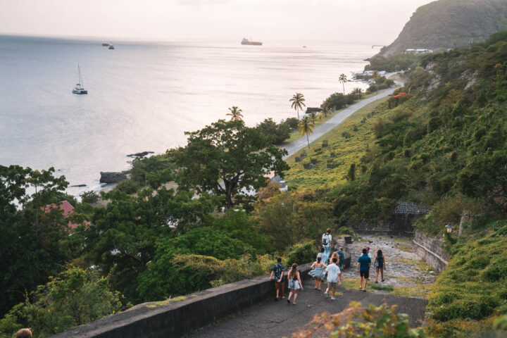 A group of people walking along a path near the ocean.