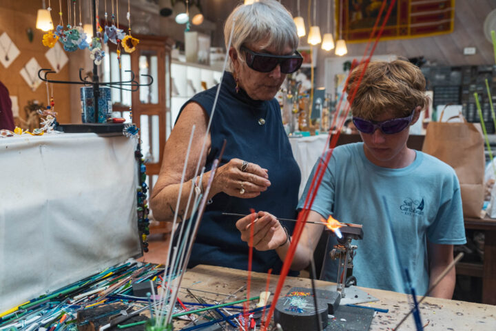 A woman and a boy are working on a piece of glass.