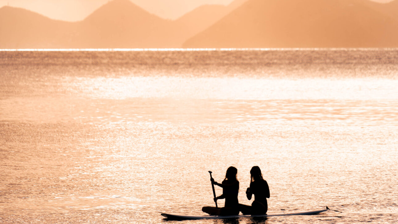 Two people on a paddle board in the water.