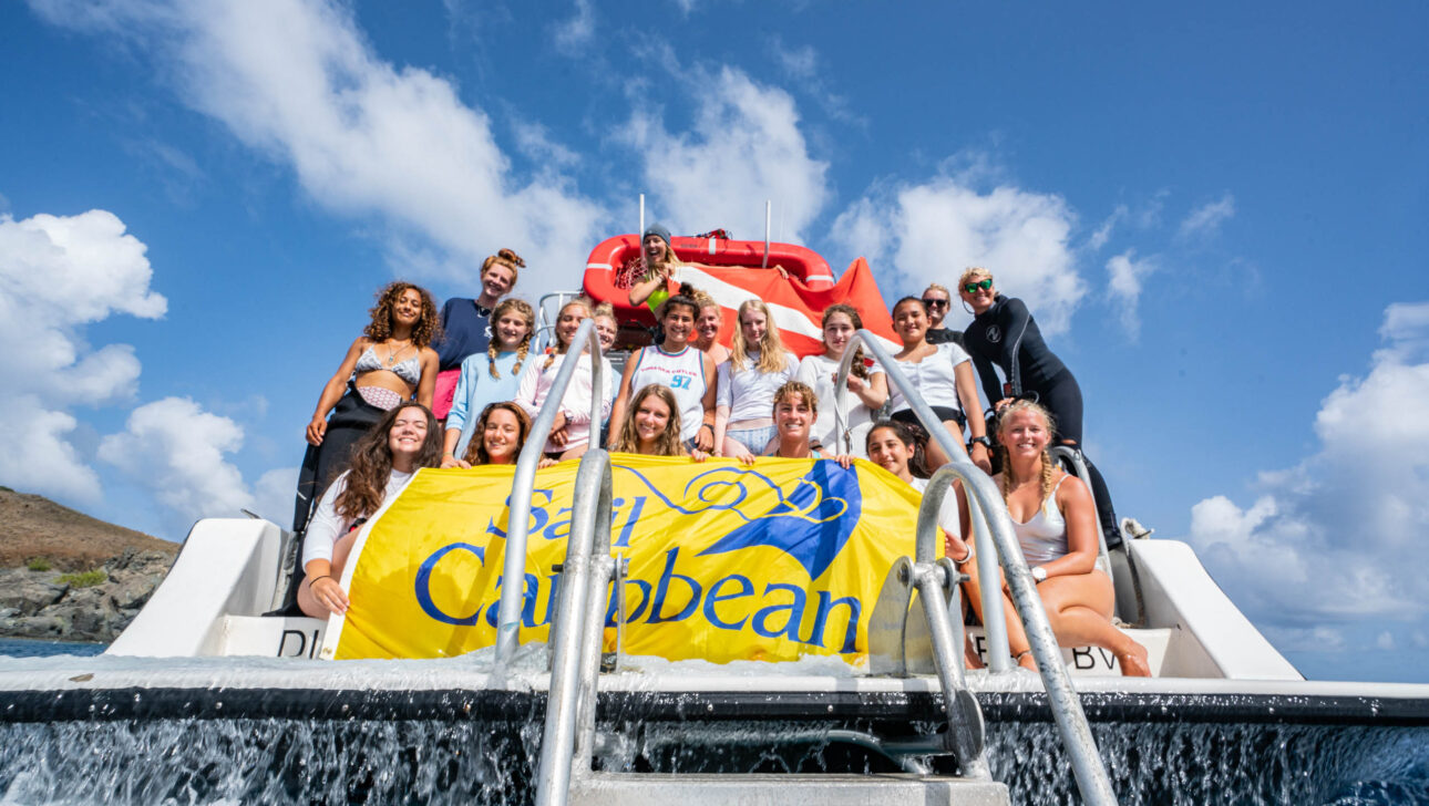 Group photo on the boat with the Sail Caribbean flag.