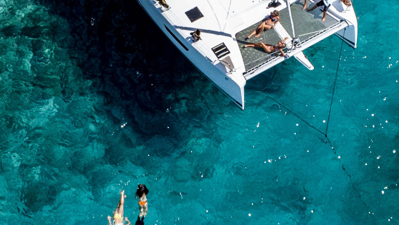 A white catamaran is floating in the water.