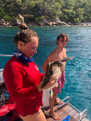 A woman holding a turtle on a boat.