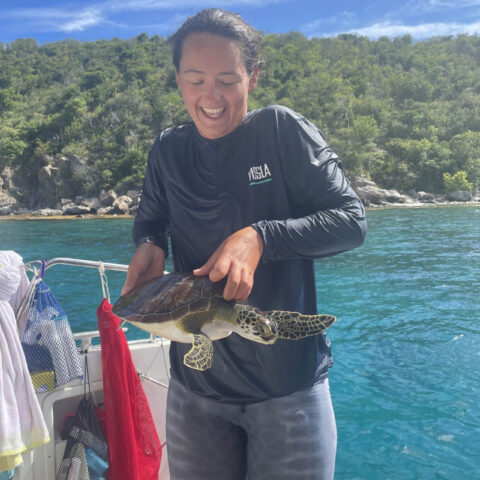 Camper holding a turtle on a boat.