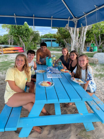 A group of campers sitting at a picnic table.