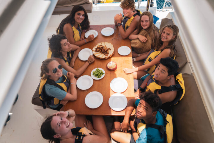 Campers sitting around a table on a boat.