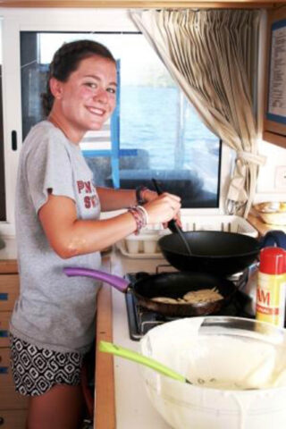 Camper preparing food in a kitchen on a boat.