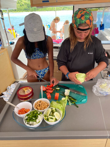 Two campers preparing food on a boat.