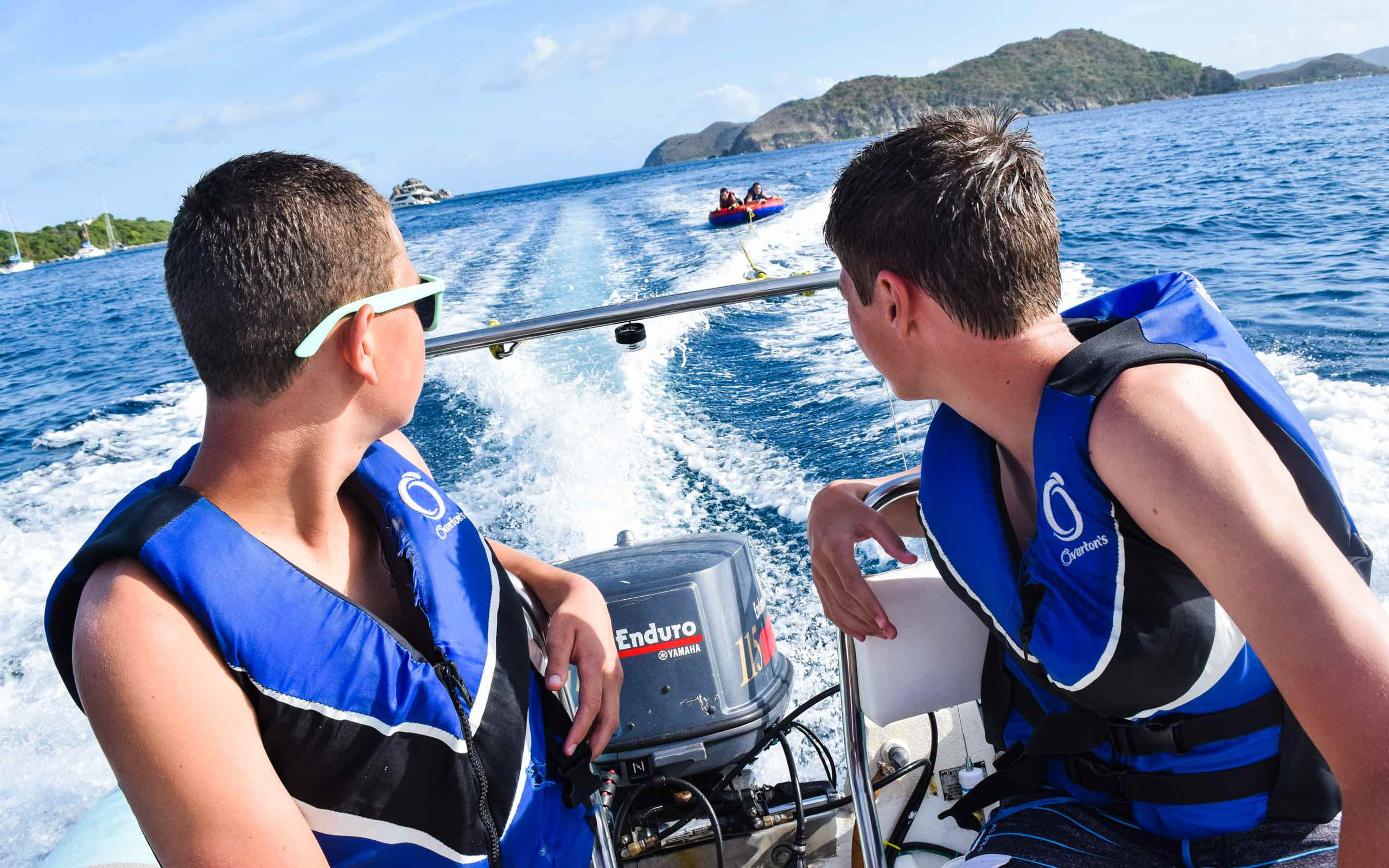Two young men on a speed boat in the ocean.