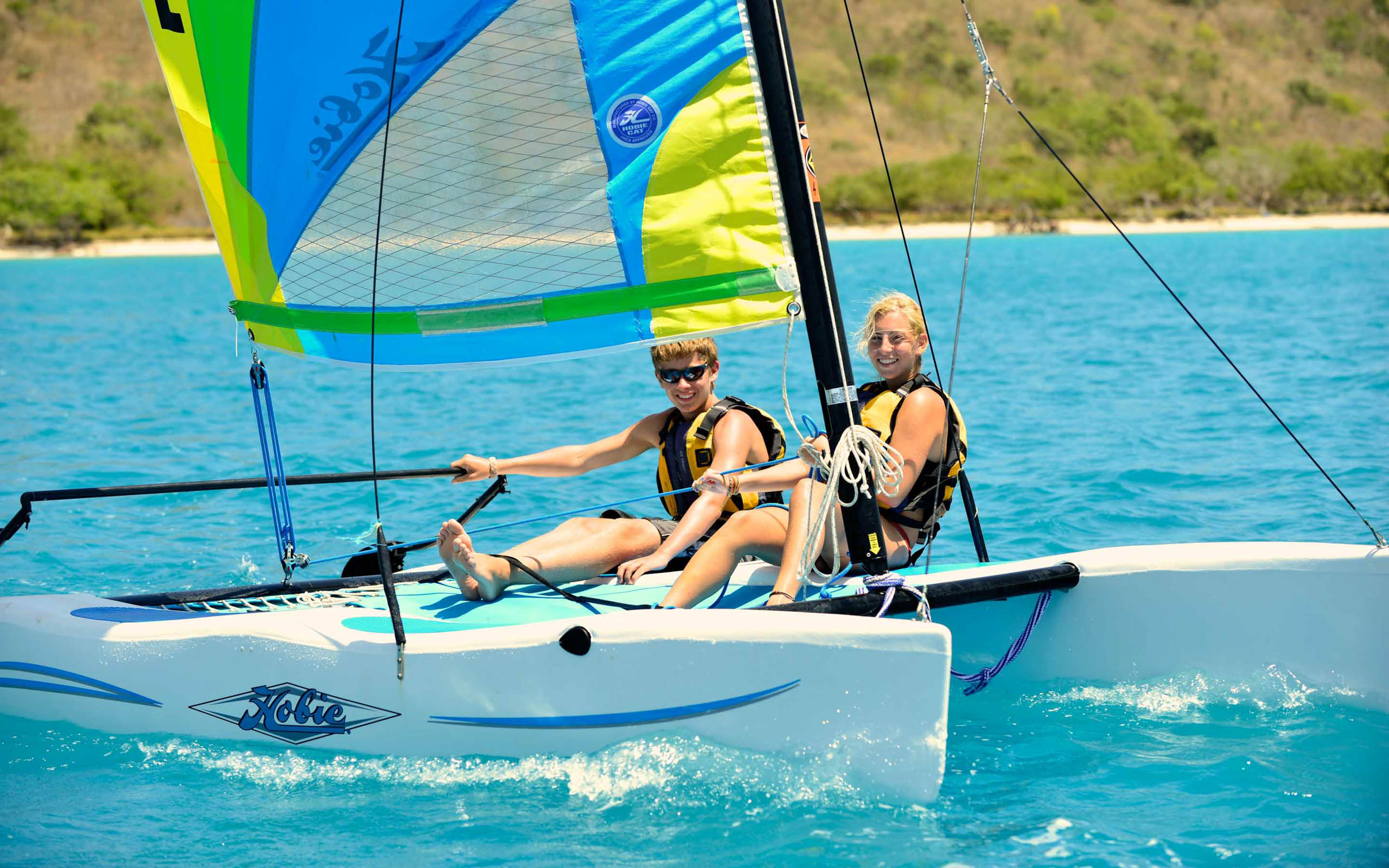 Two people on a sailboat in the water.