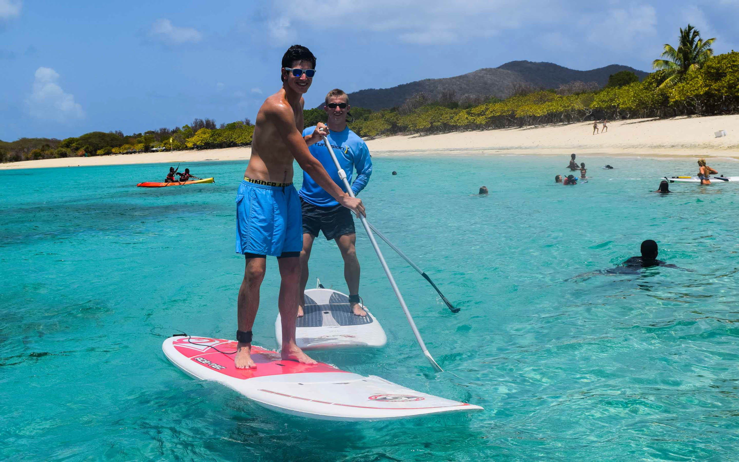 Two people stand up paddle boarding in the water.