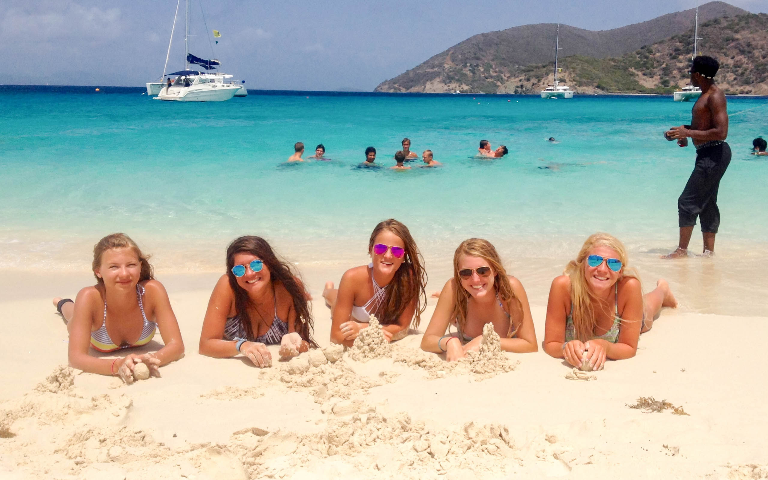A group of girls laying on the sand on a beach.