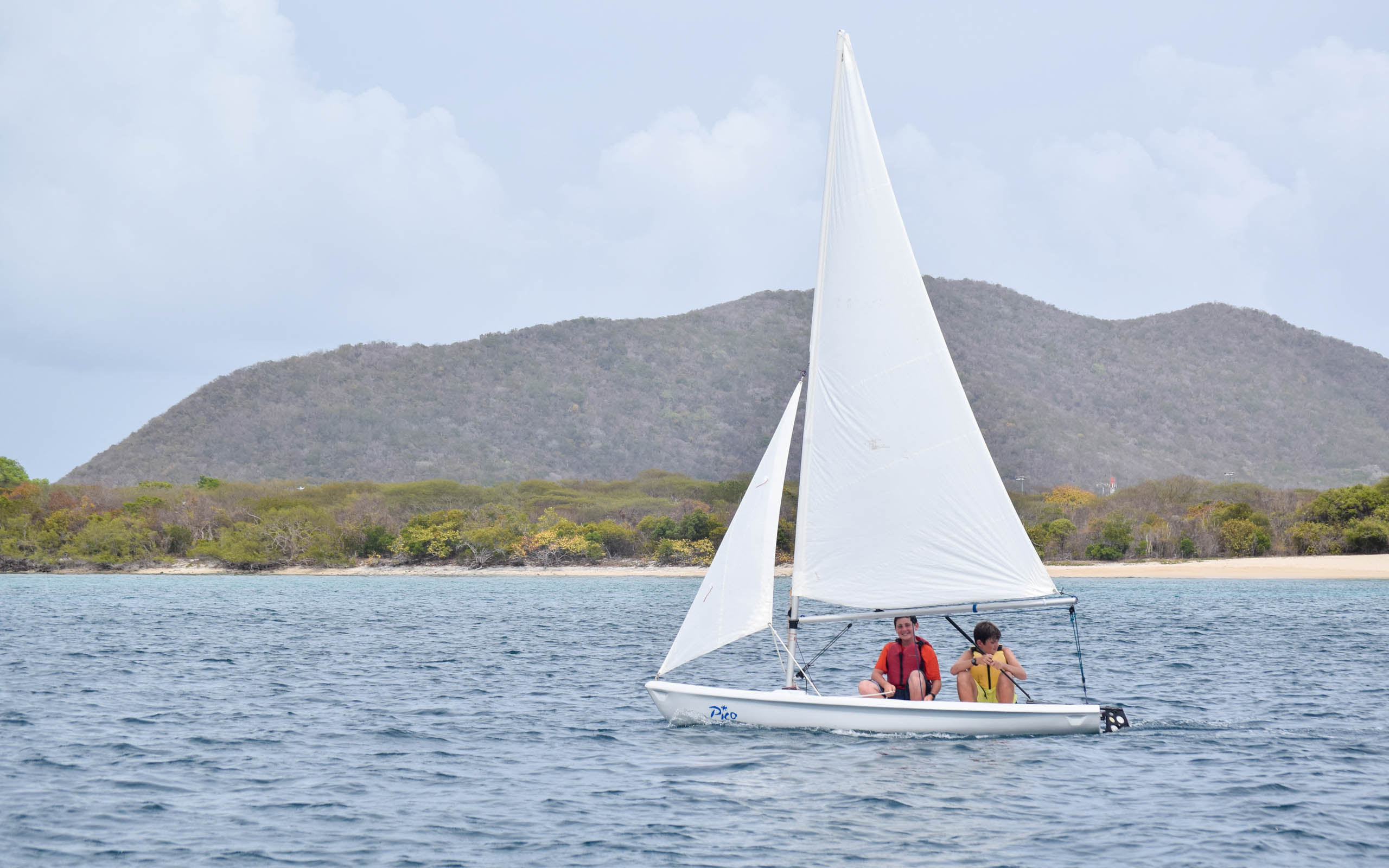 A couple of people on a sailboat on a lake.