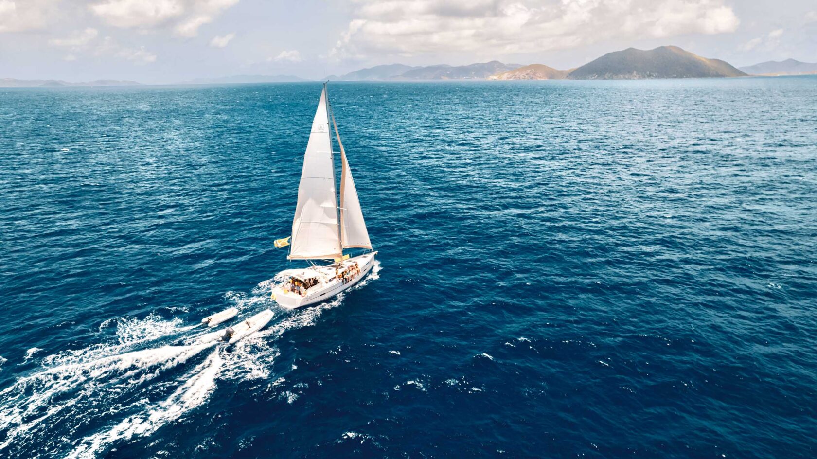 An aerial view of a sailboat sailing in the ocean.