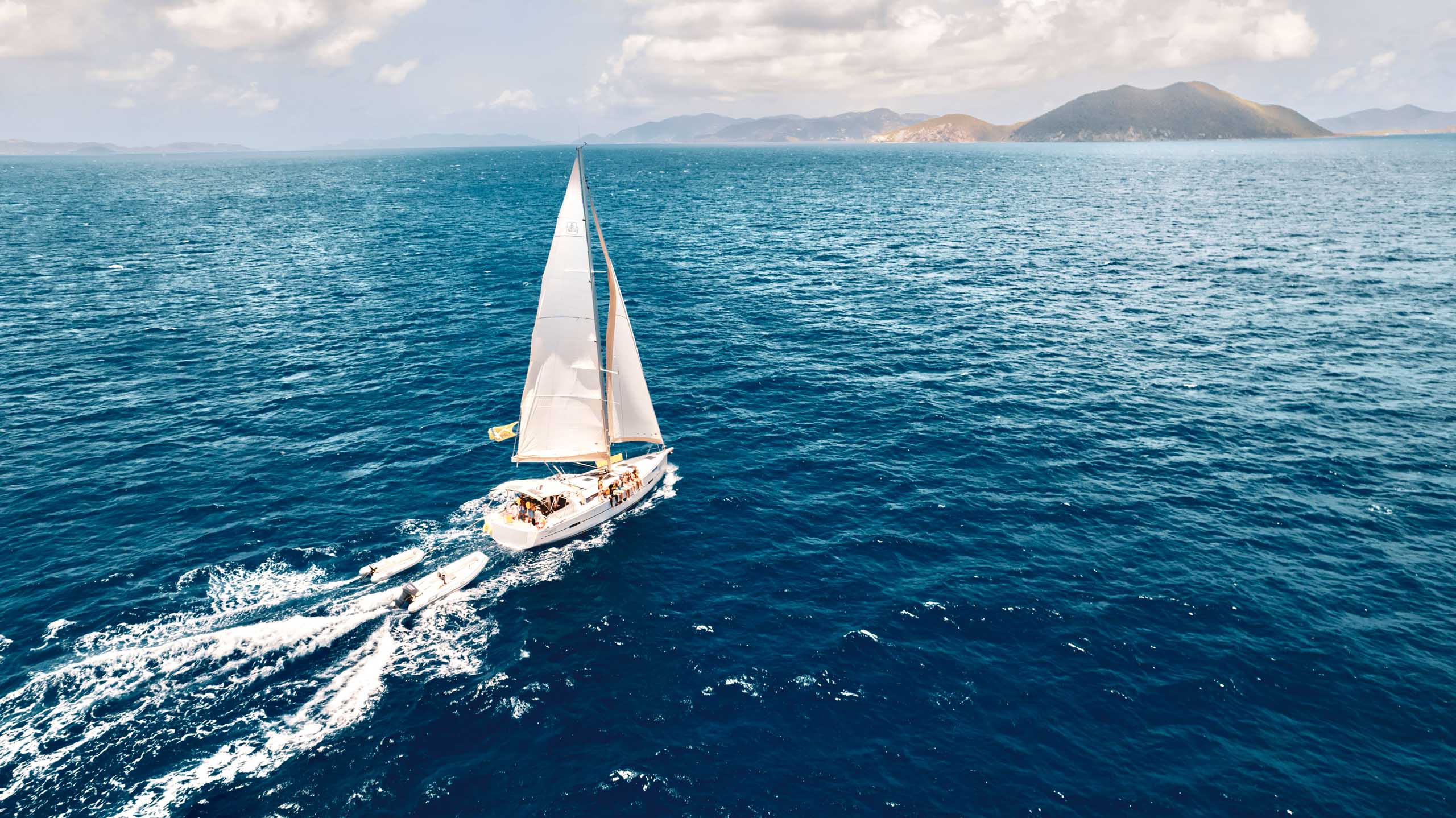 An aerial view of a sailboat sailing in the ocean.