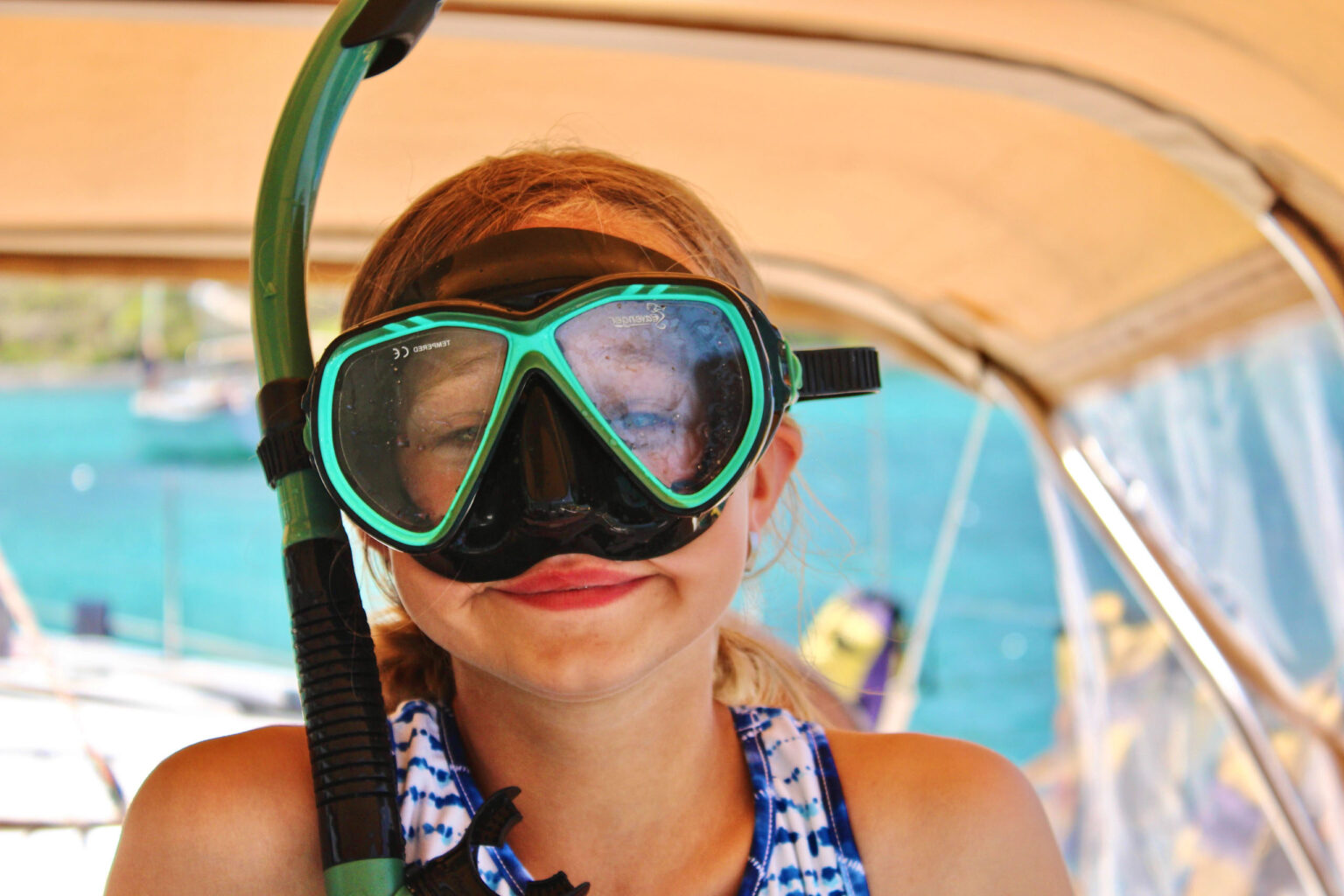 A young girl wearing a snorkel and snork on a boat.