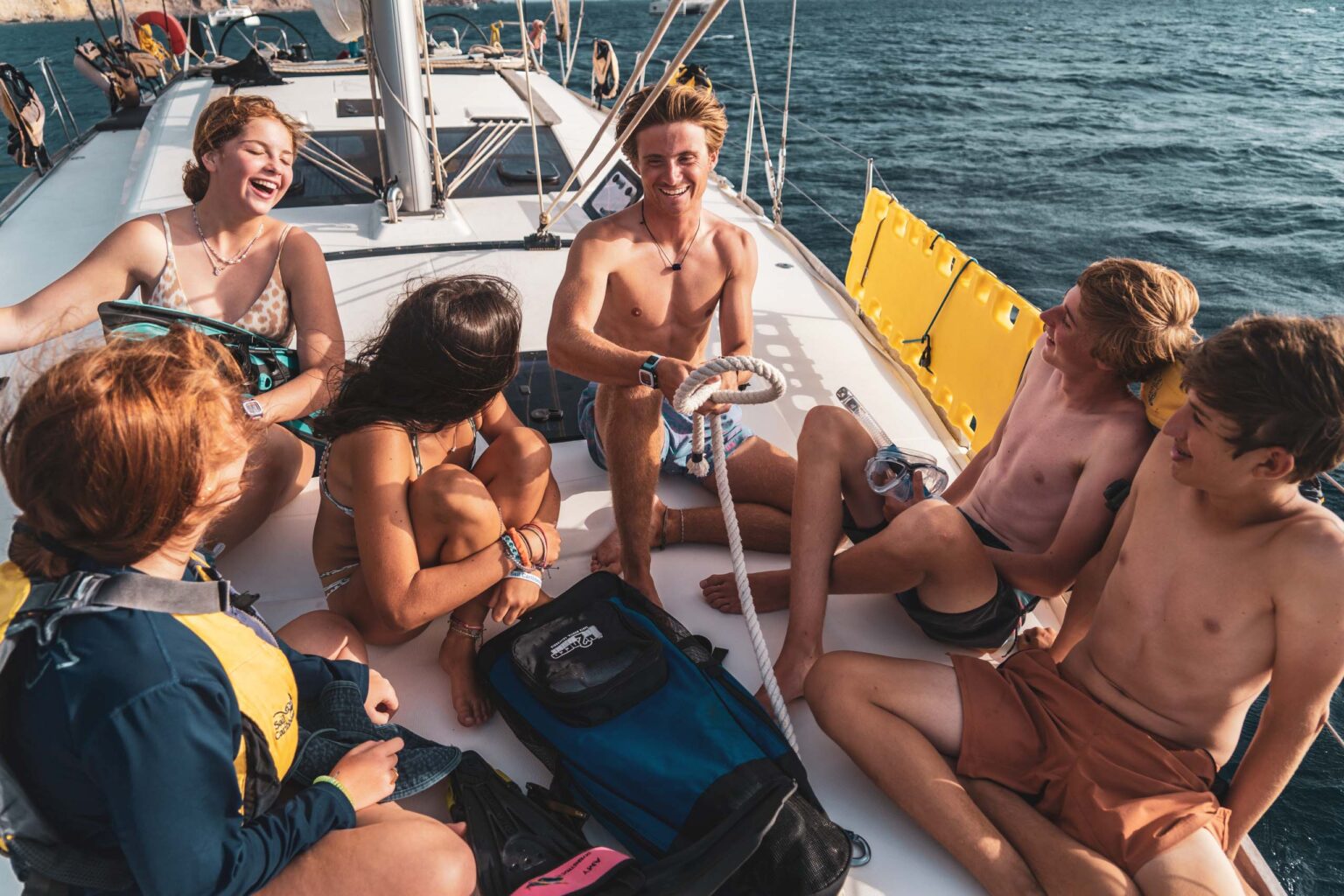 A group of people sitting on the back of a sailboat.