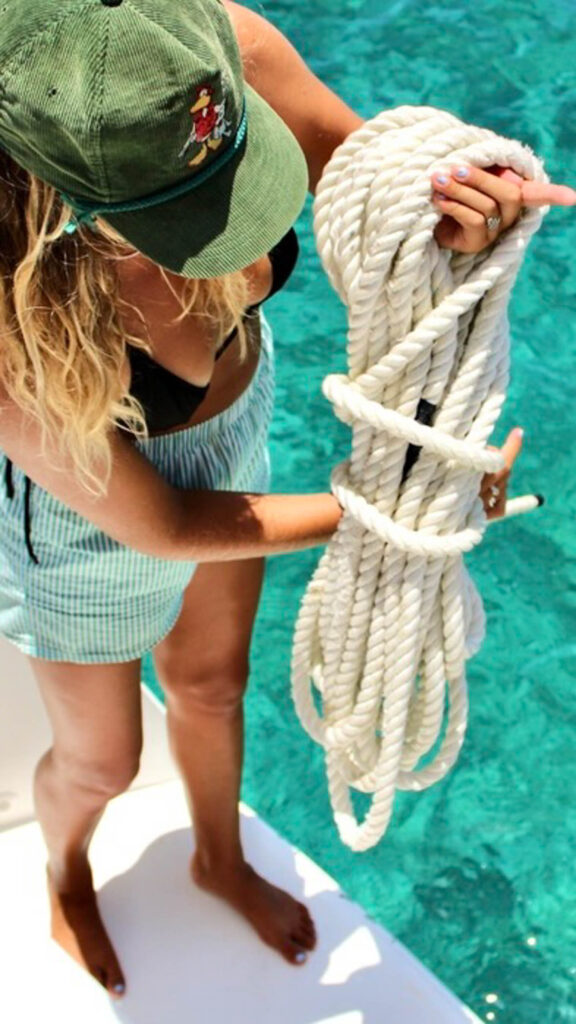 A woman holding a rope on a boat in the ocean.