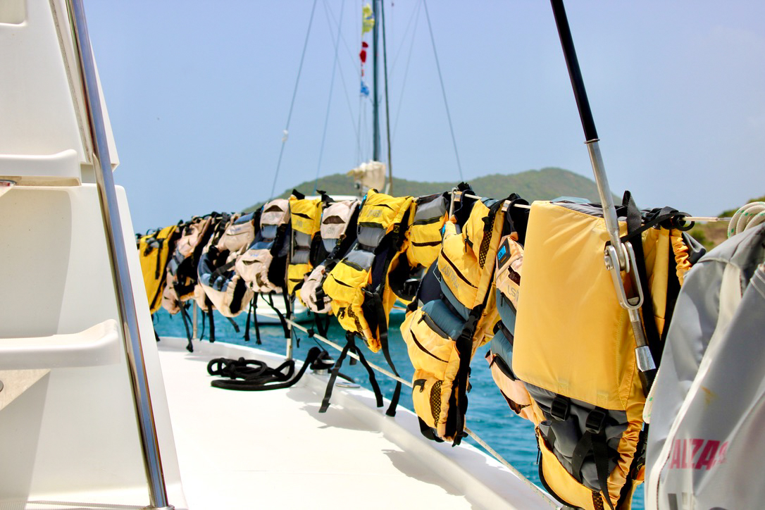 Yellow life jackets hanging on the side of a boat.