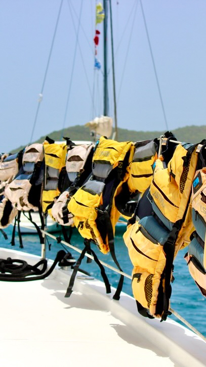 A group of yellow and black life jackets on the deck of a boat.