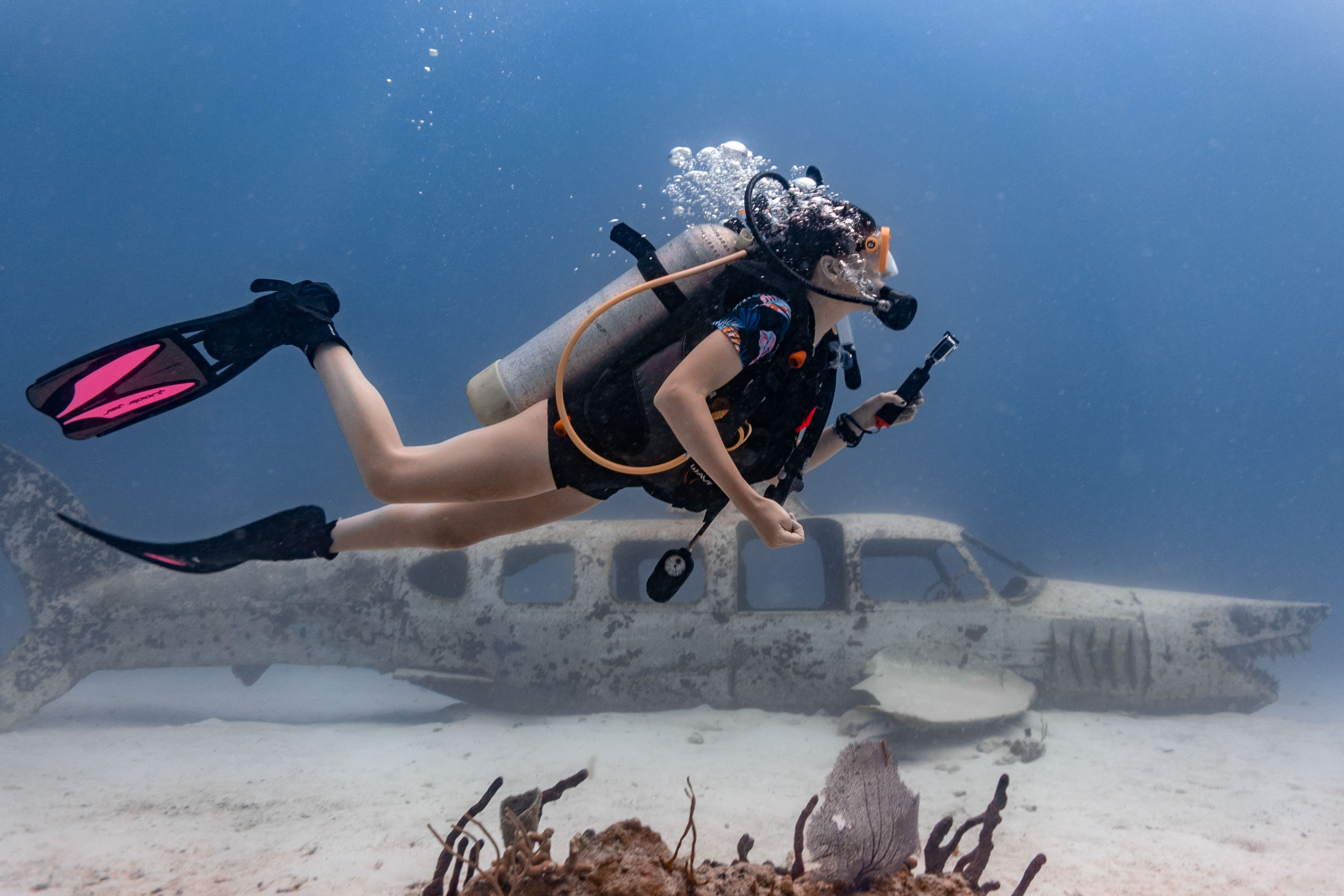 A woman scuba diving near an old airplane.
