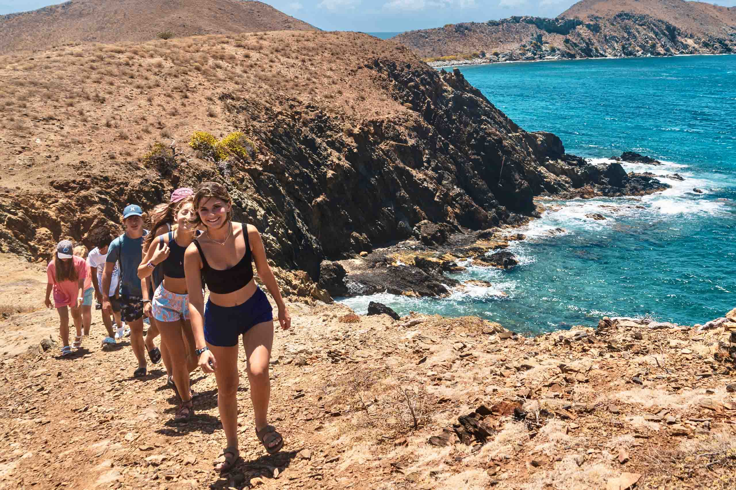 A group of people hiking along a trail near the ocean.